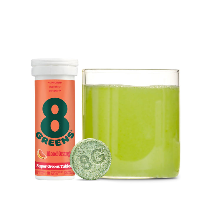 Super Greens Tablets in flavor blood orange with glass cup with water and tablet mixed in