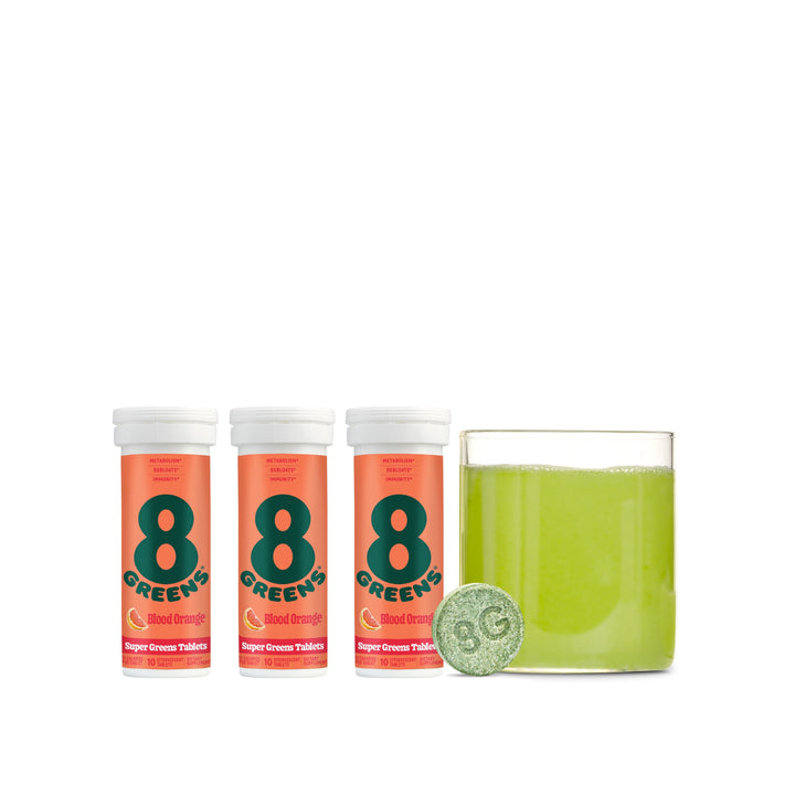 3 tubes of tablets in super greens tablets flavor blood orange with glass cup with water and tablet mixed in 